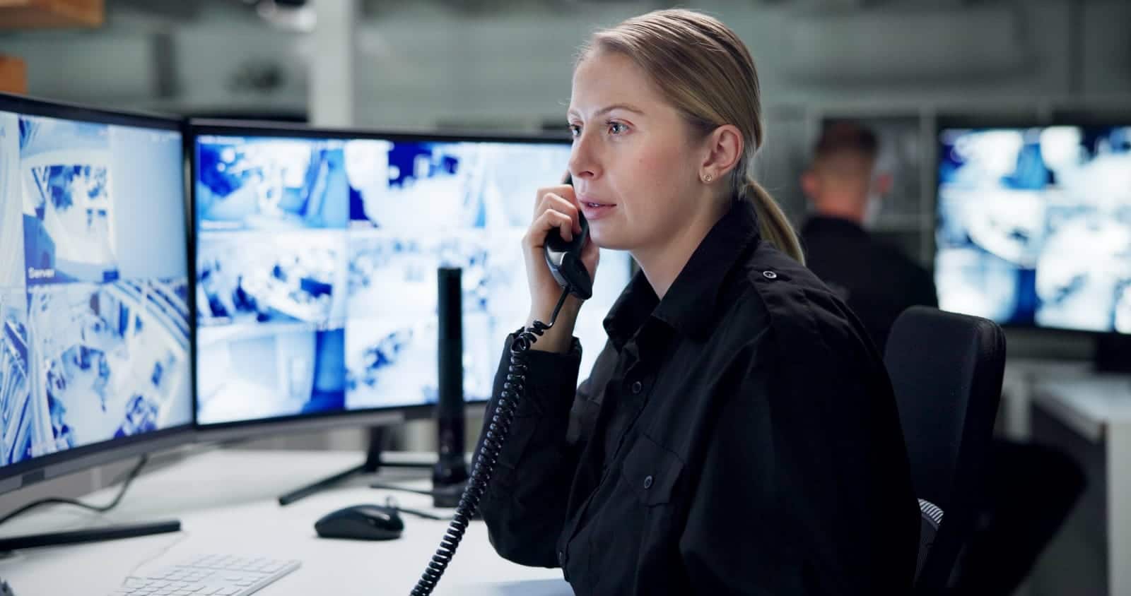 A woman makes a phone call in a security system control room.