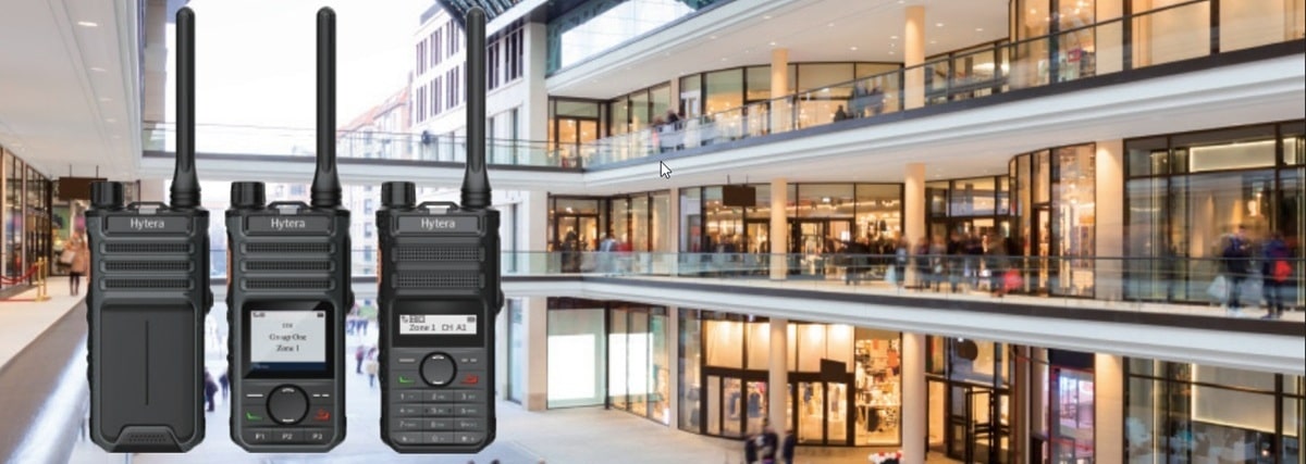 Hytera digital radios displayed in front of a modern multi-level shopping mall, highlighting their use in retail and security communications.